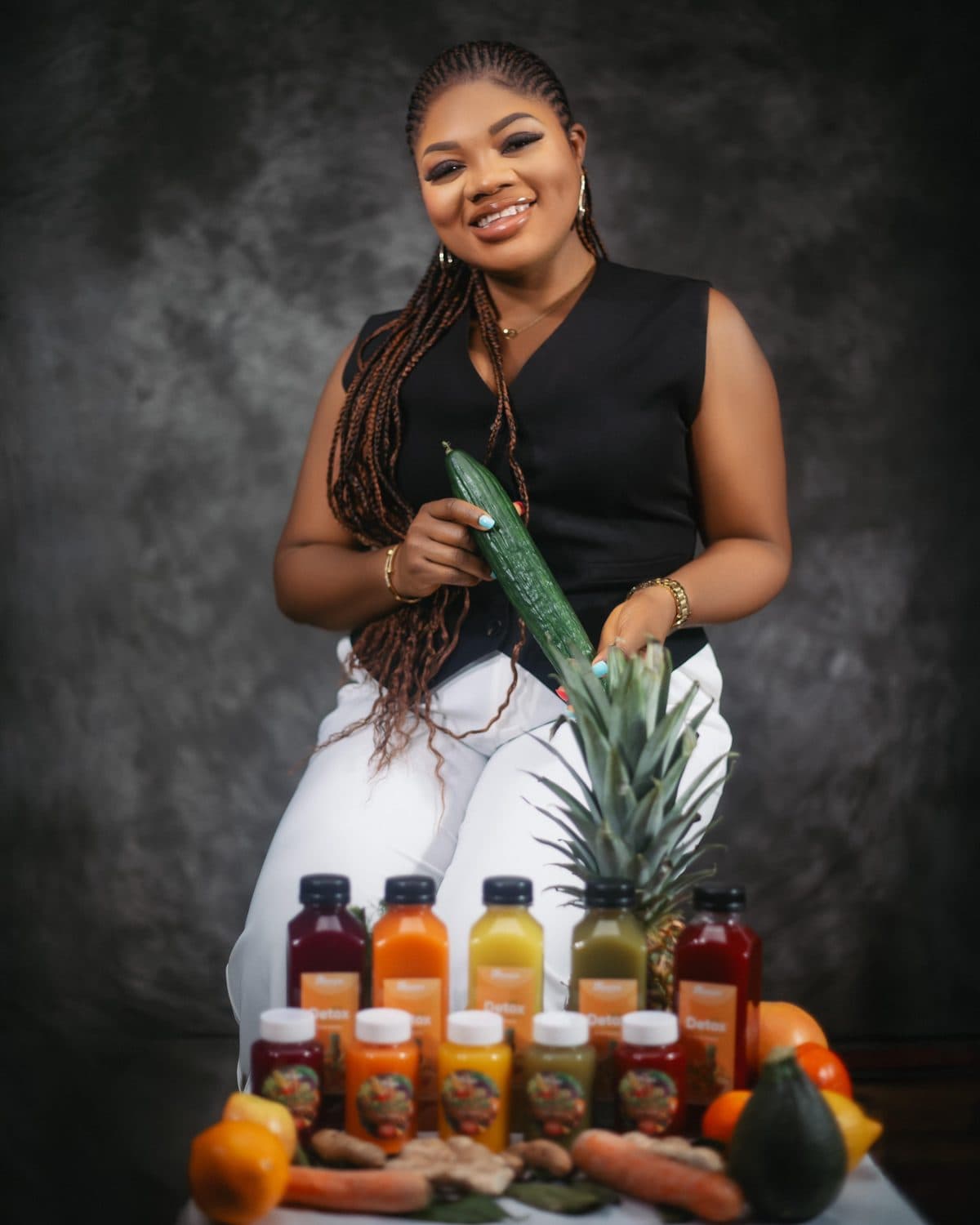 La fondatrice de Nanou Detox derrière sa gamme de jus, entourée de fruits et de légumes frais.