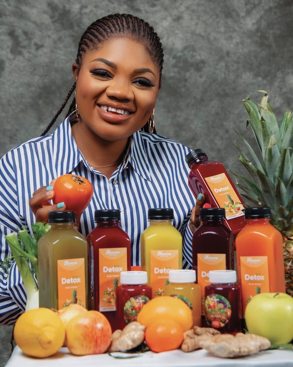 Nanou, fondatrice de Nanou Detox, derrière sa gamme de jus, entourée de fruits et de légumes frais.